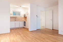 Leerer Wohnraum mit verlegtem Eichenparkett, Blick in Küche und Flur